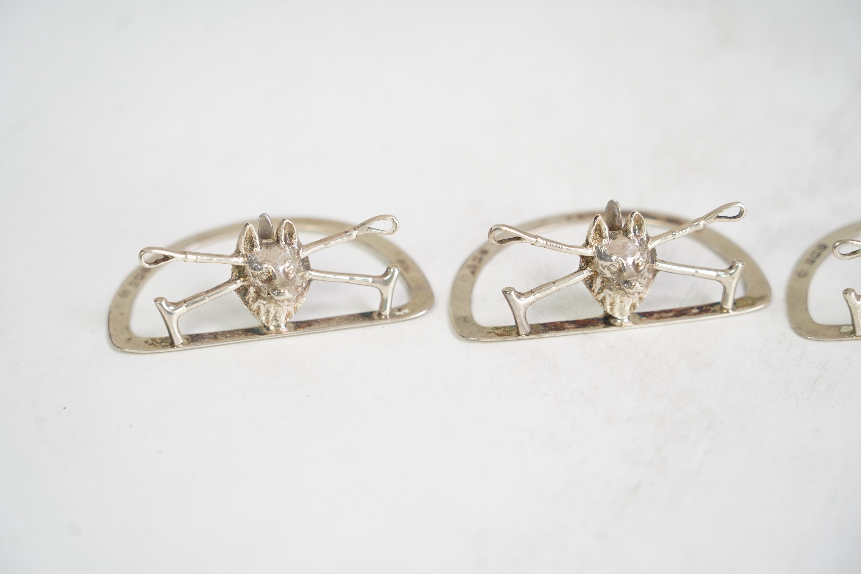 A cased set of four George V silver menu holders, modelled as a fox head with crossed riding crops, by William Hutton & Sons